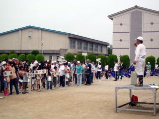 内部小学校の校庭に集まった大勢の人。挨拶するのは社会福祉協議会木田会長